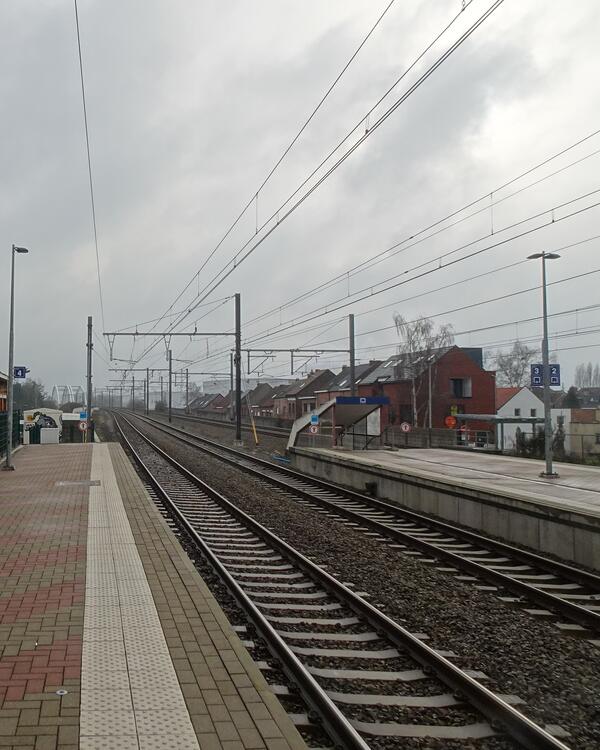 Perron en sporen van station Duffel onder een grijze lucht