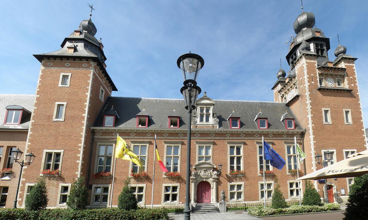 Het gemeentehuis van Duffel, een bakstenen gebouw met twee torens en vlaggen